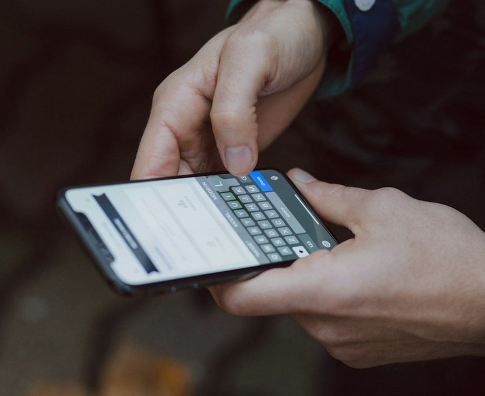 Mãos digitando uma mensagem em um celular