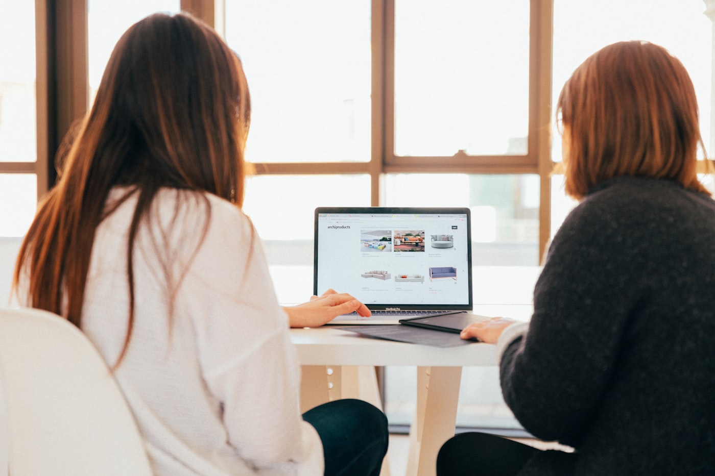 Two people reviewing work together on a laptop