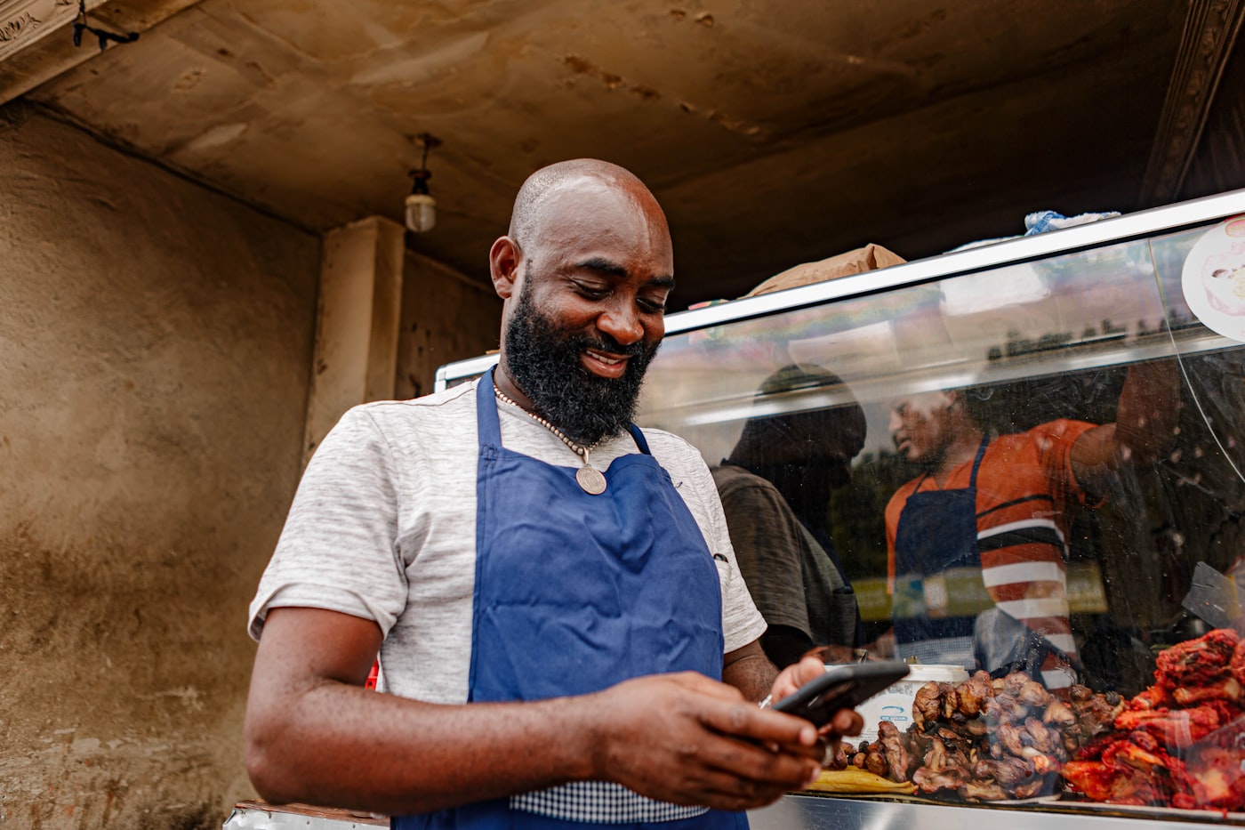 Shop owner in an apron checking messages on a mobile phone